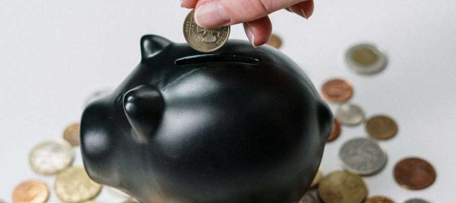 a person putting money into a black piggy bank