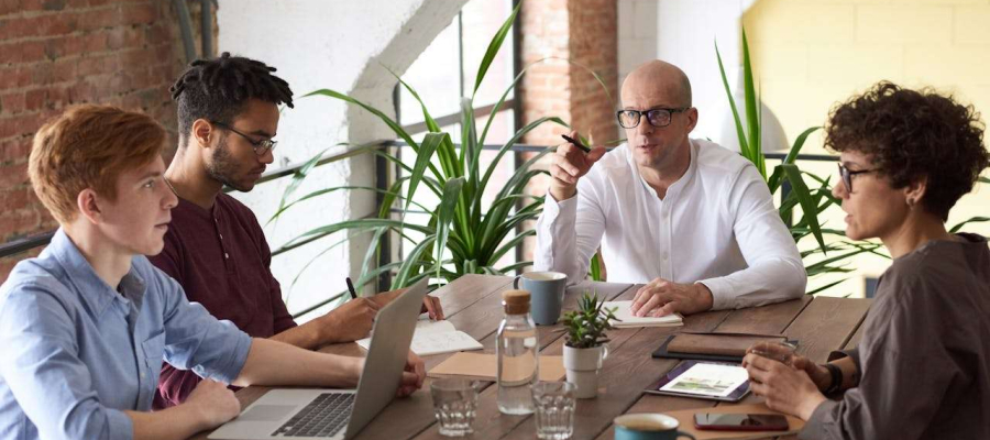 four people sitting around a table having a meeting.