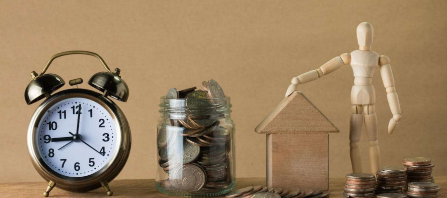 a clock with a jar of money and a house