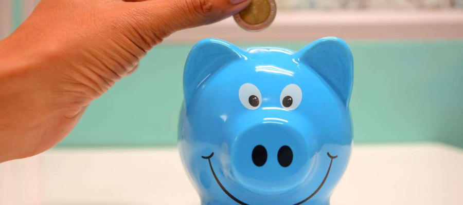 a coin going into a savings box. This is in the shape of a pig