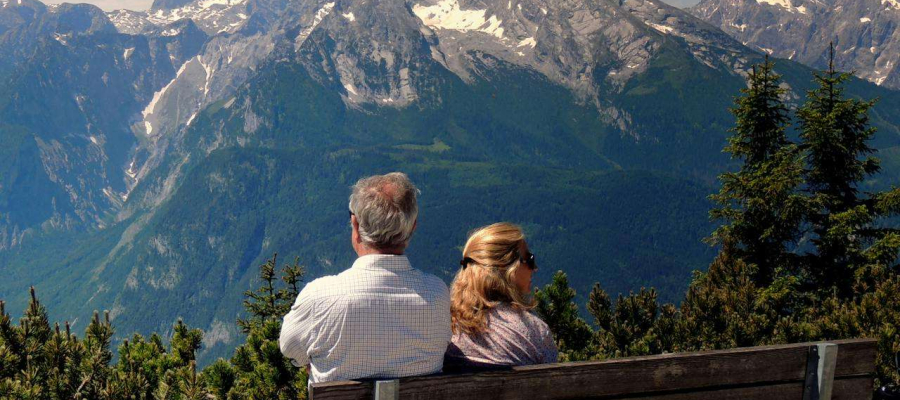 a couple sitting on a bench in front of a mountain