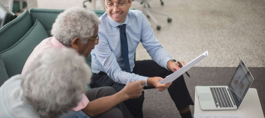 elderly couple speaking with a financial adviser