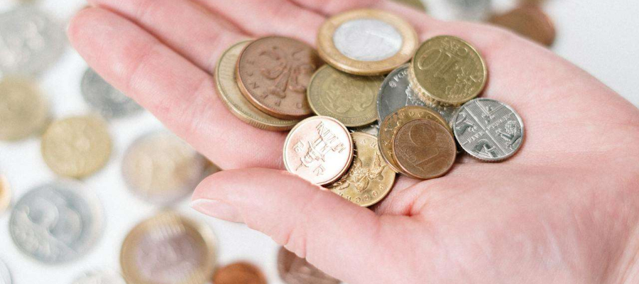 a hand holding a variety of coins