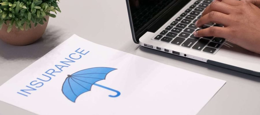 paper showing insurance next to a laptop