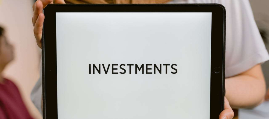 a person holding an ipad that has the word investment written on it