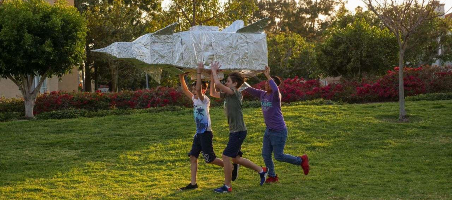 kids holding a rocket ship running across the yard
