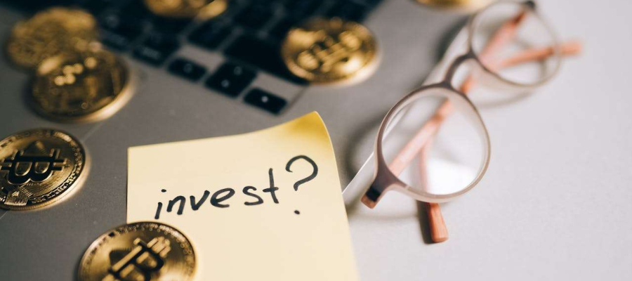 a laptop with money, glasses and the word invest
