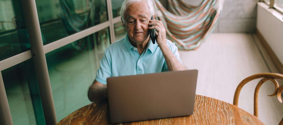 an older person working with their laptop and phone
