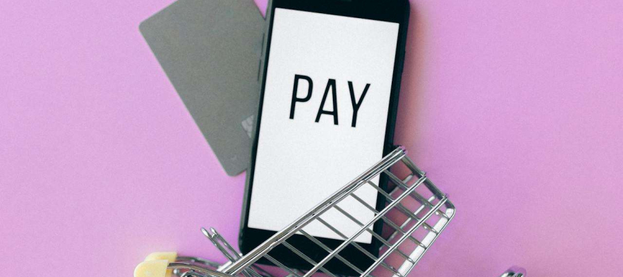 Mobile phone in a trolley displaying the word pay
