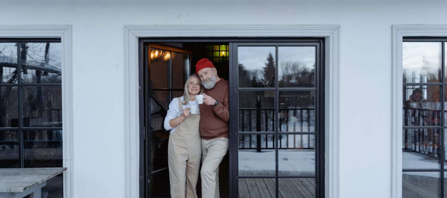 A retired couple looking comfortable drinking a warm drink.