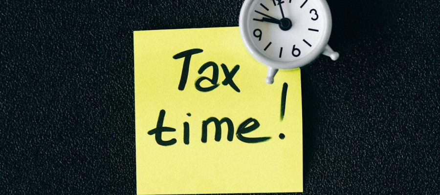 a sticky note with the words "tax time" written on it along with a clock