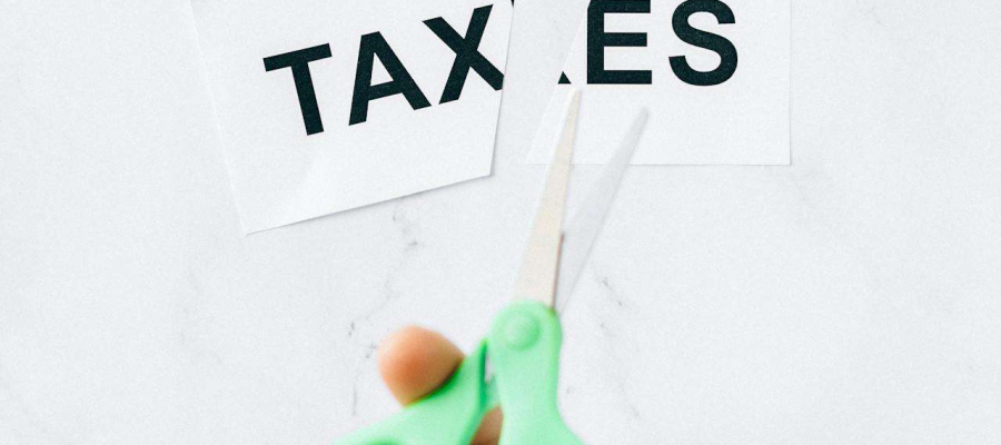 a person cutting the word taxes in half using scissors