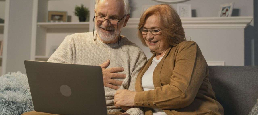 two people sitting on a sofa looking at a laptop