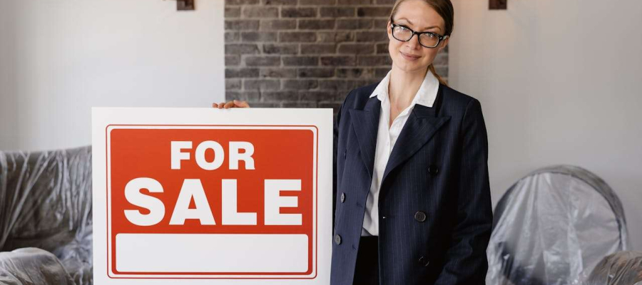 a woman holding a for sale sign.