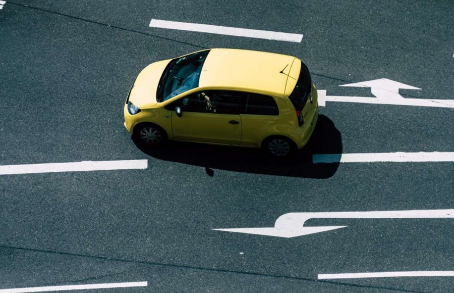 A Yellow Car Driving On A Road