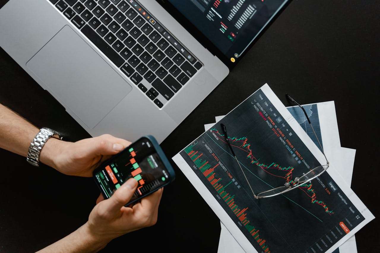 an image showing market charts on paper and on a phone