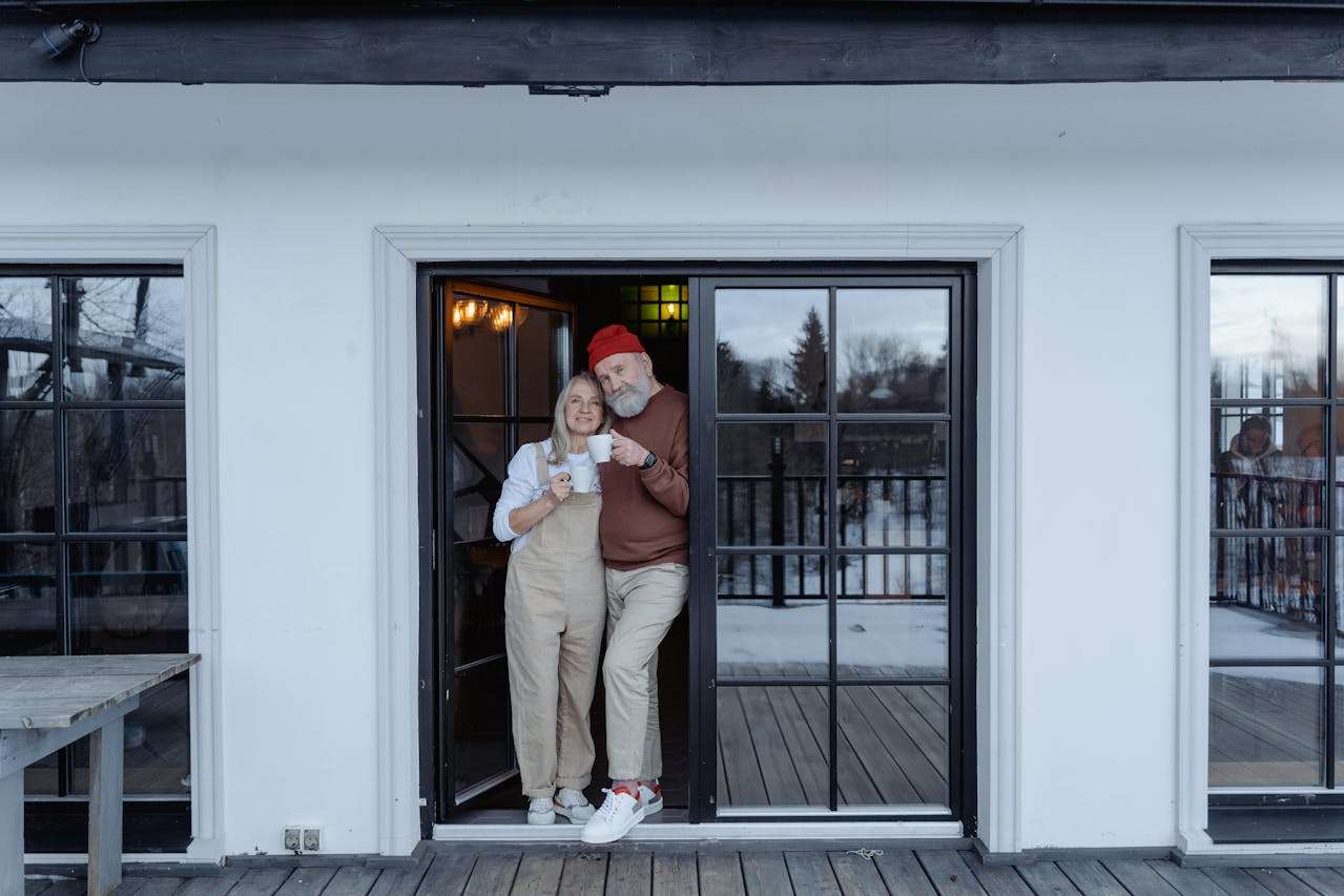 A retired couple looking comfortable drinking a warm drink.