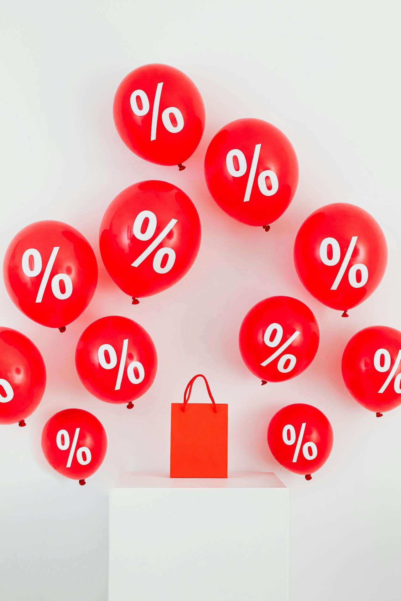 bag on podium surrounded by balloons that have a percentage mark on them.