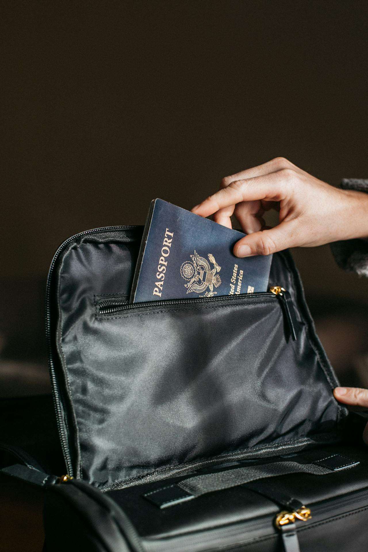 a person putting a passport into a black bag