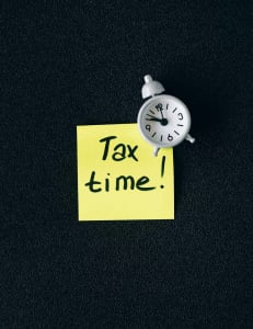 a sticky note with the words "tax time" written on it along with a clock