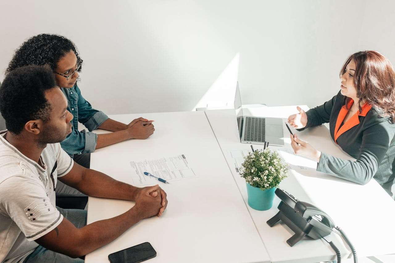 three people sitting at a table having a meeting.