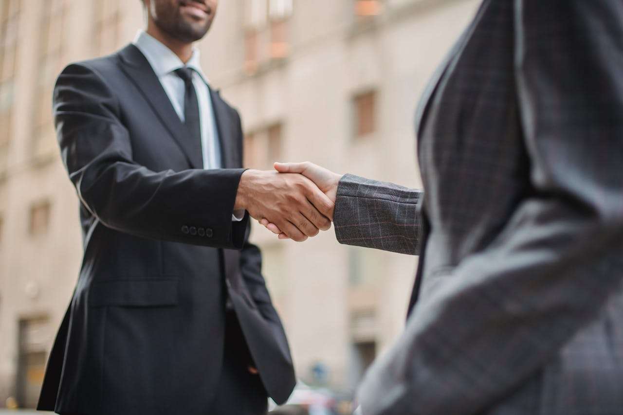 two men in suits shaking hands on the street