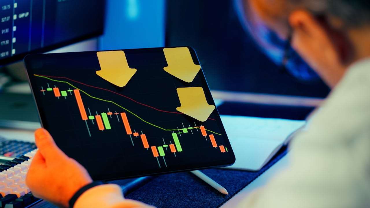 a person sitting with a tablet that is showing a market downturn