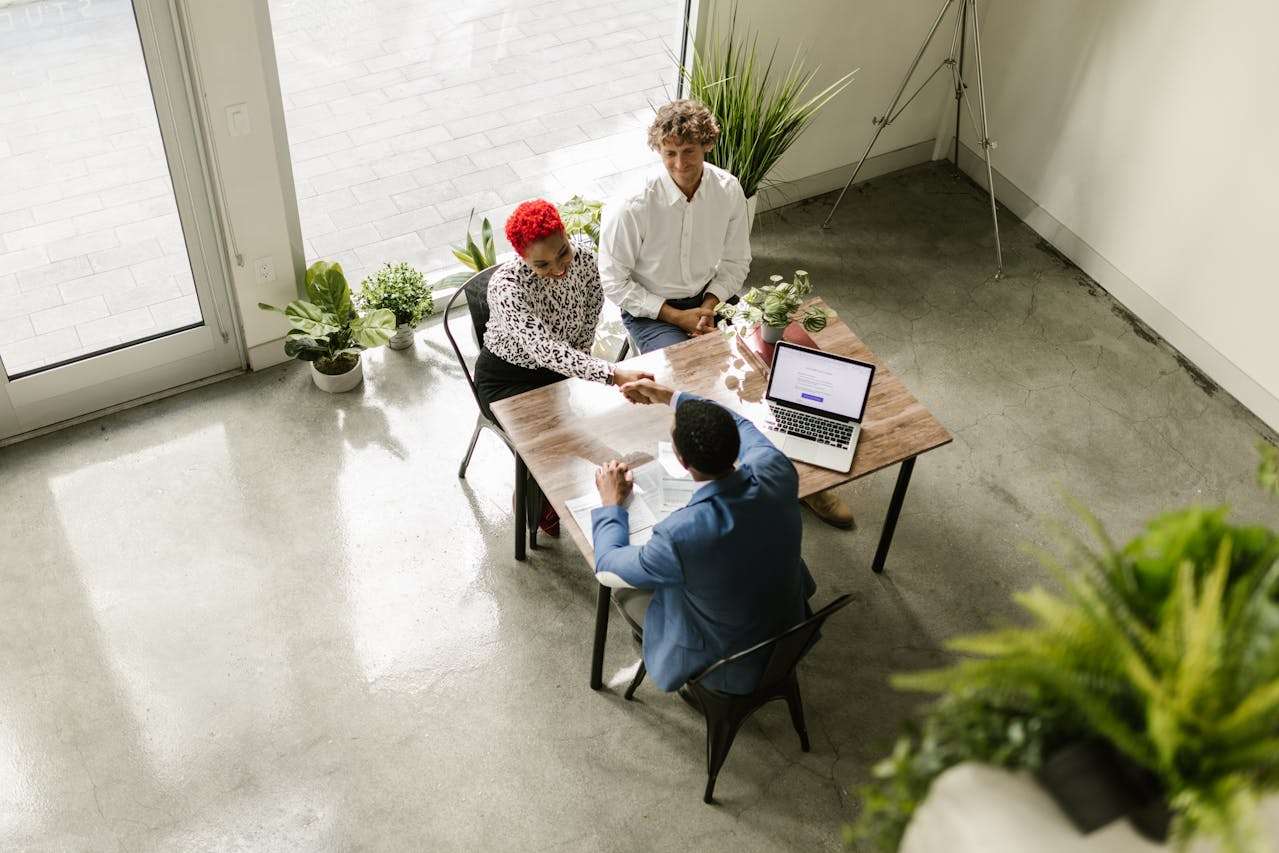 three people sitting around a table making a deal.