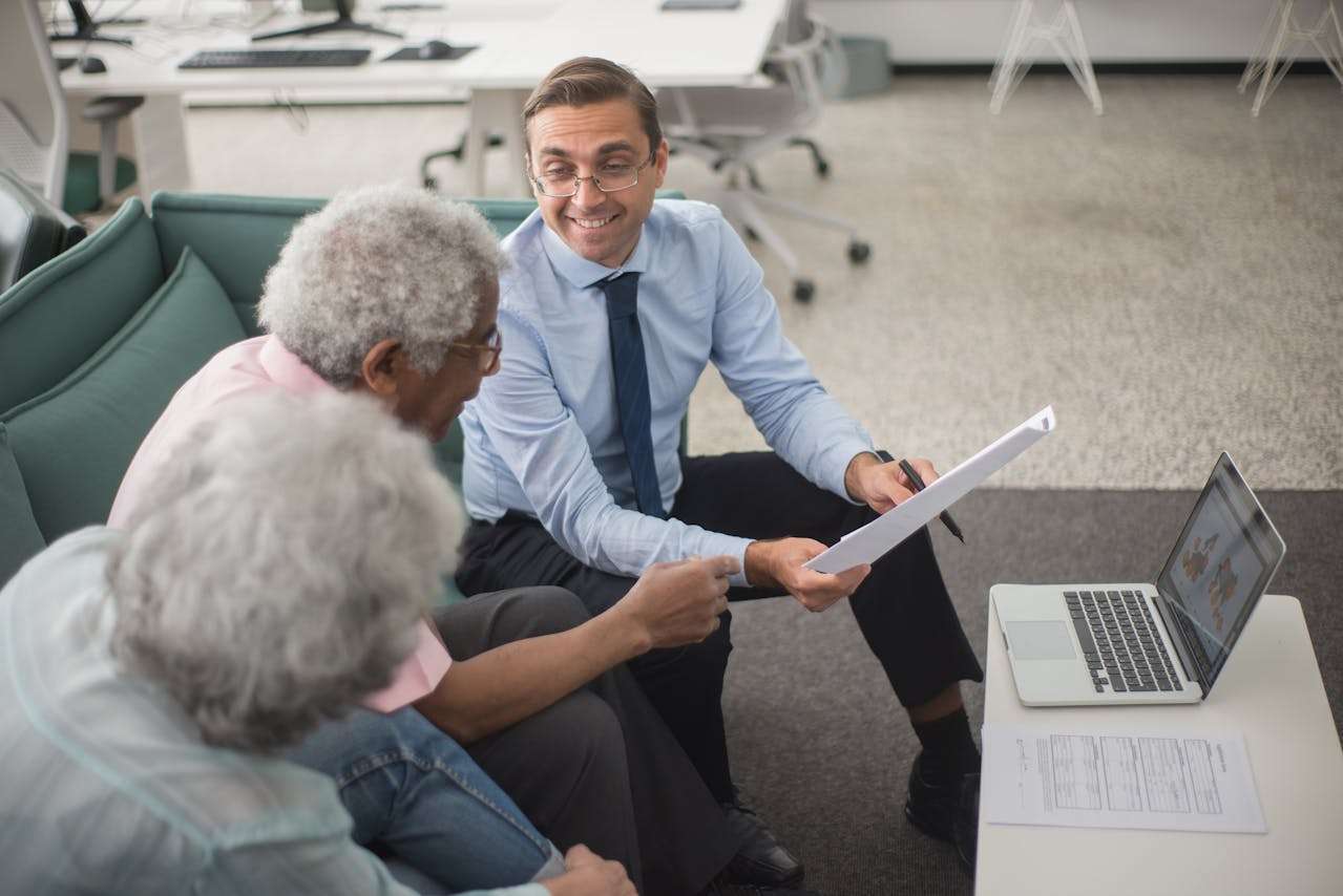elderly couple speaking with a financial adviser