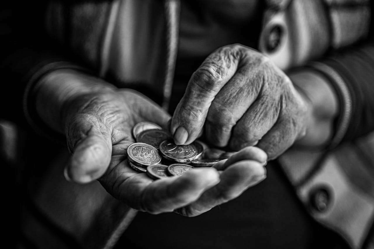 elderly person holding a hand full of coins