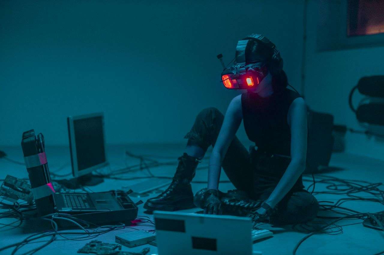 a person with a VR headset on surrounded by different laptops and computers