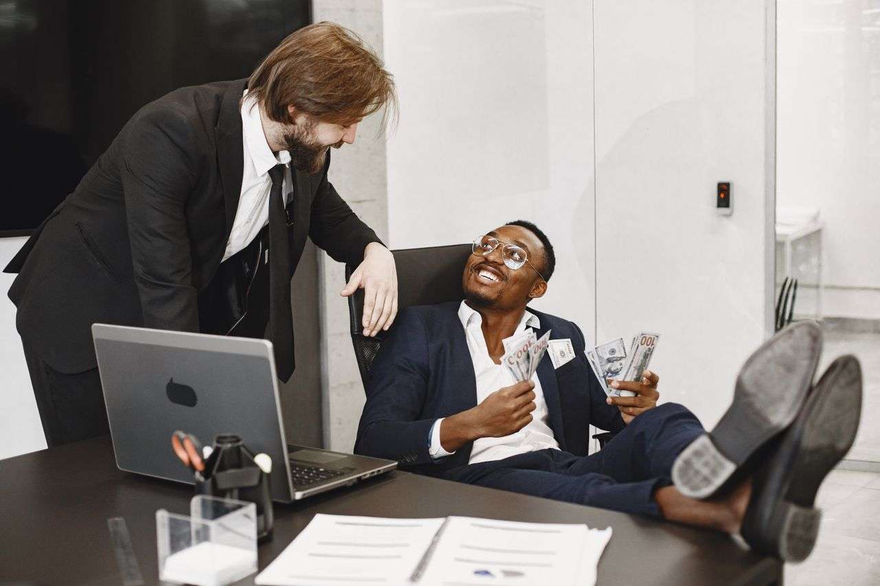 two people in an office. One person holding handful of money