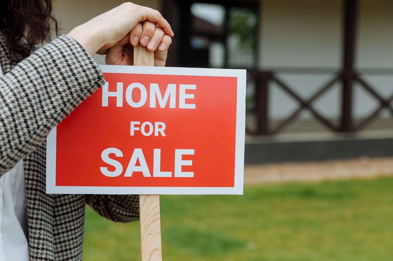 A for sale sign being put outside a home