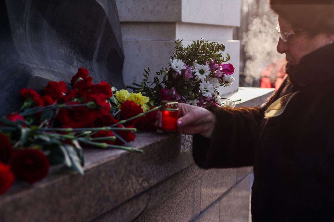 A lady at a cemetery placing flowers on a grave