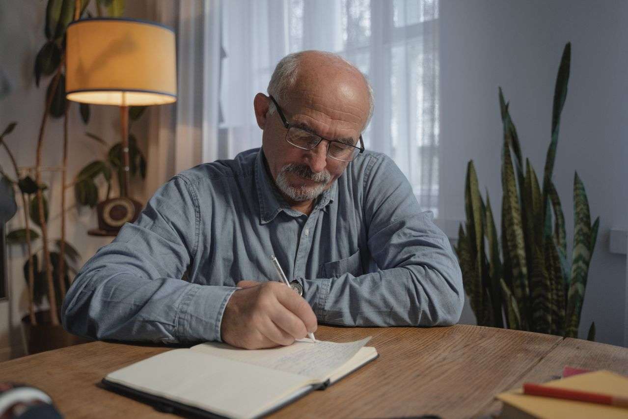 A Man Writing In A Notebook