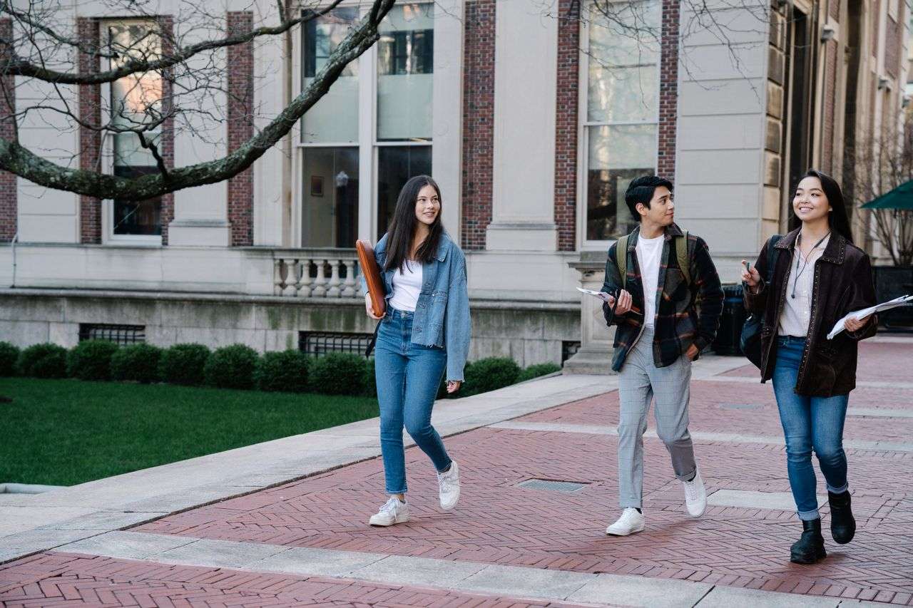 three students walking across a university campus